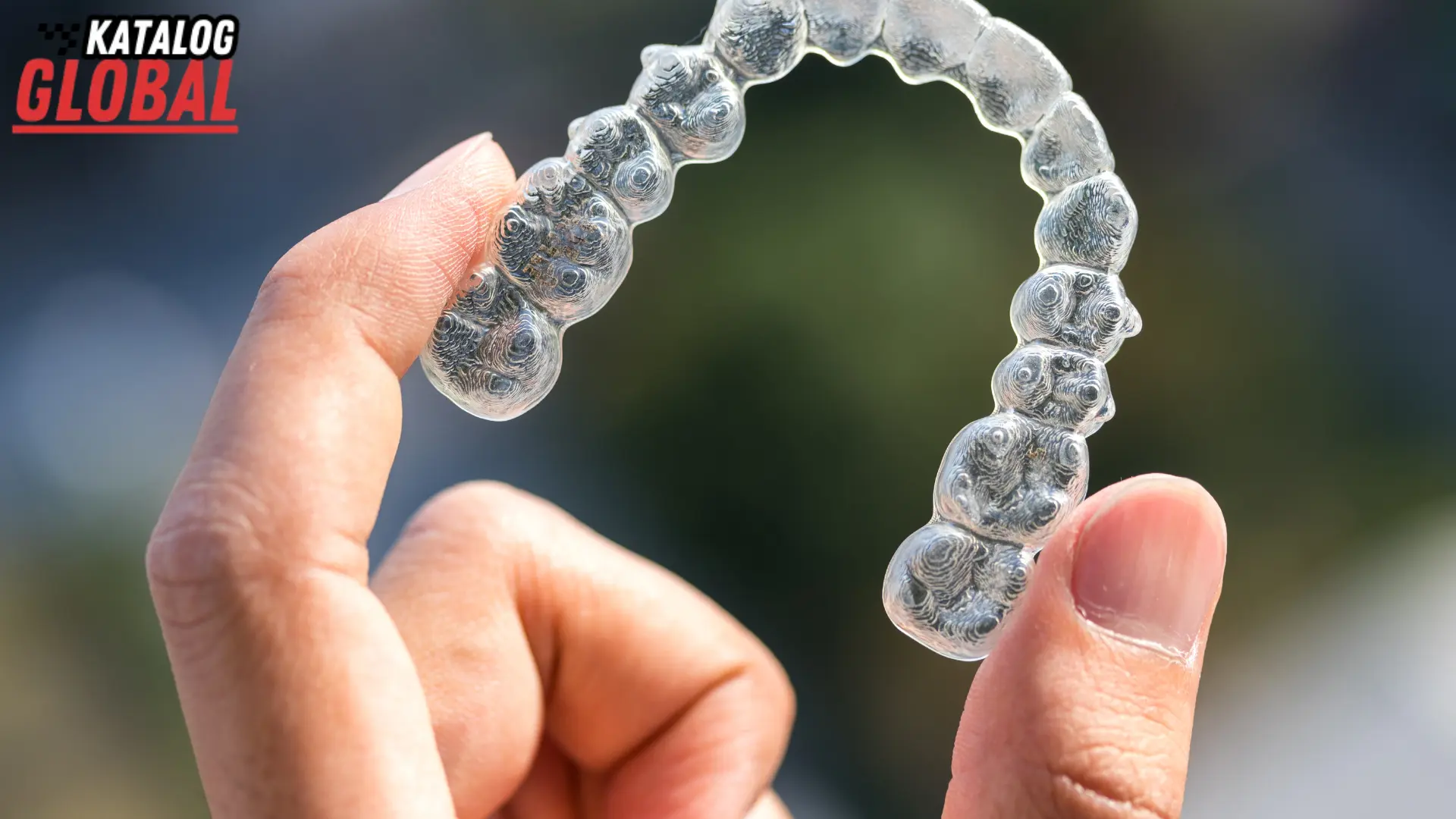 A close-up of a hand holding a clear Invisalign aligner, highlighting the question, "How Much Does Invisalign Cost Without Insurance?